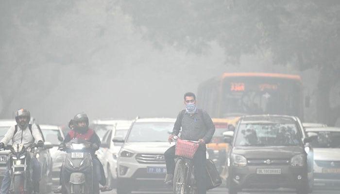 People stopped on a road while heavy smog can be seen. — AFP/file