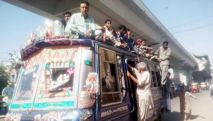 Passengers travelling on the roof of an overloaded bus in Karachi, on November 30, 2022. — PPI