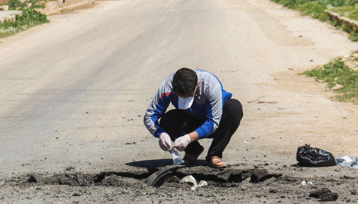 A Syrian man collects samples from the site of the suspected toxic gas attack in Khan Sheikhun. — AFP/File