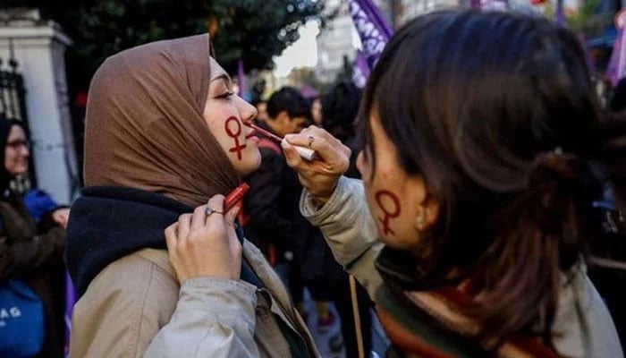 A protester paints the female gender symbol on the face of a woman during a demonstration to mark the International Day for Elimination of Violence against Women, in Istanbul. — AFP/file