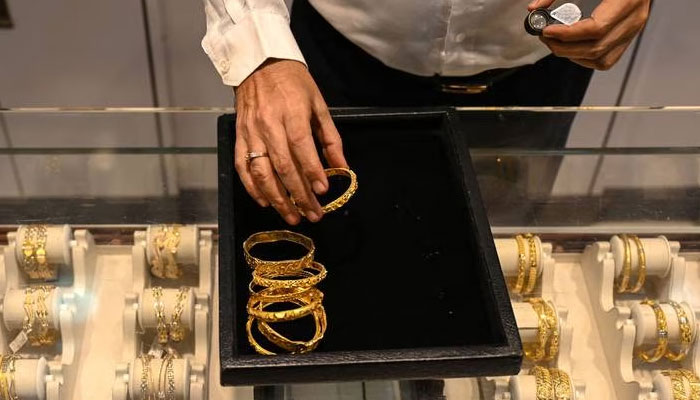 A salesperson displays gold jewellery at a store in this undated file photo. — AFP/File