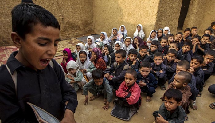 A boy recites from a book during a lesson at a school in a slum on the outskirts of Islamabad on October 11, 2013.— Reuters