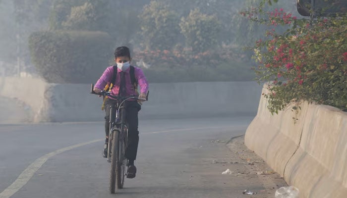 Student rides a bicycle to school amid dense smog in Lahore, Pakistan on November 24, 2021. — Reuters