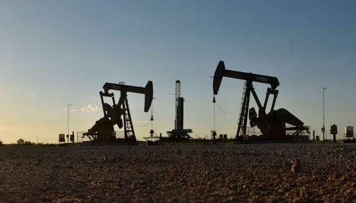 Pump jacks operate in front of a drilling rig in an oil field. — Reuters/File