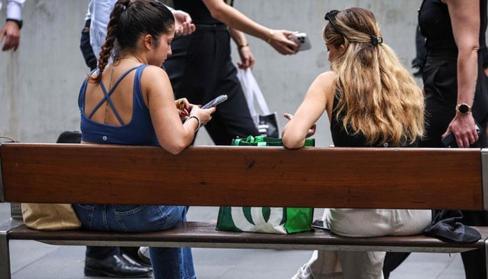 Girls can be seen using mobile phone. — AFP/File