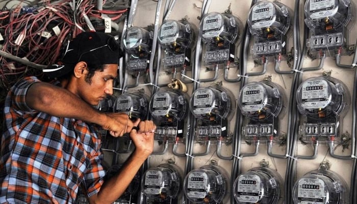 An electrician can be seen fitting electric meters. — AFP/File