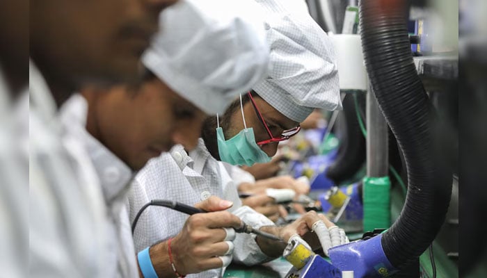 Representational image shows workers solder wires on printed circuit boards of a mobile handset. — Reuters/File