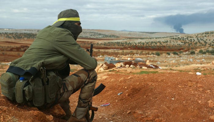 A fighter from Hayat Tahrir al-Sham (HTS) mans a position in the eastern outskirts of Atarib town, in Syrias Aleppo province, as smoke rises in the distance during clashes with the Syrian army. — AFP/File