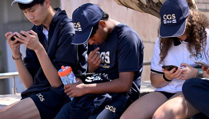 Australian children looking busy in using mobile phones. — AFP/File