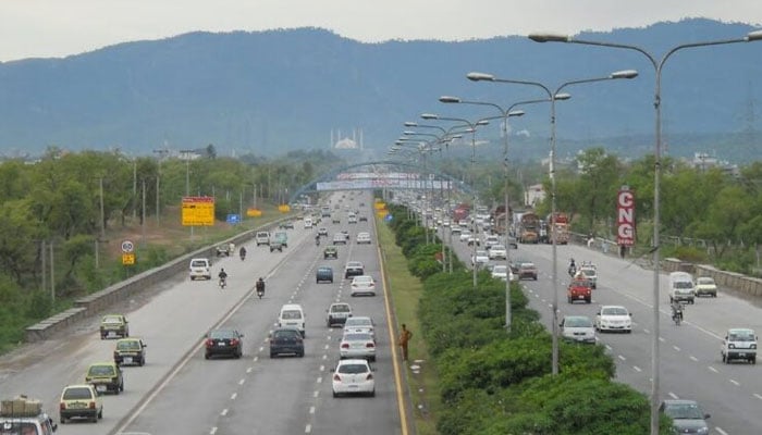 Commuters make their way along a road in Islamabad. — APP/File