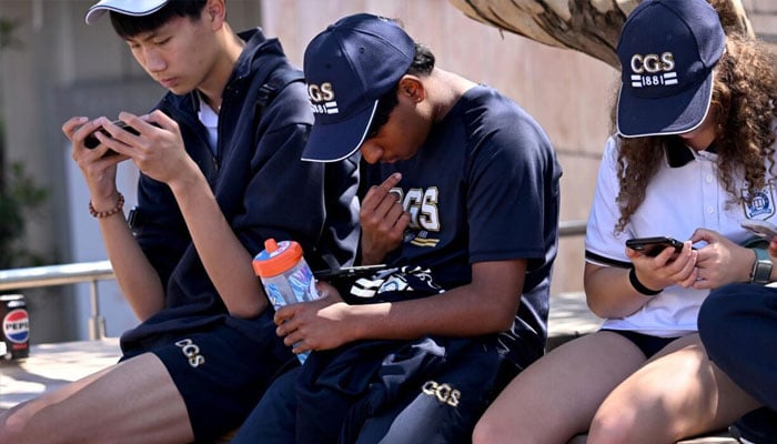 Students look at their phones in Australia. — AFP/File