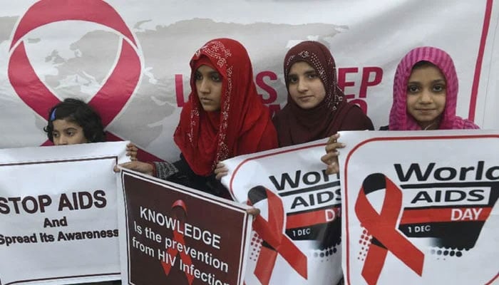 Young children carry placards as Pakistani social activists take out a rally to raise awareness on World AIDS Day in Lahore on December 1, 2016. — AFP