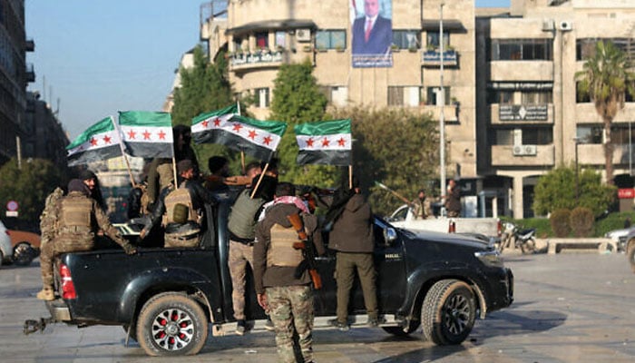 Anti-government fighters wave opposition flags in Syrias northern city of Aleppo on November 30, 2024, amid a lightning offensive against forces of the Iranian- and Russian-backed government. — AFP