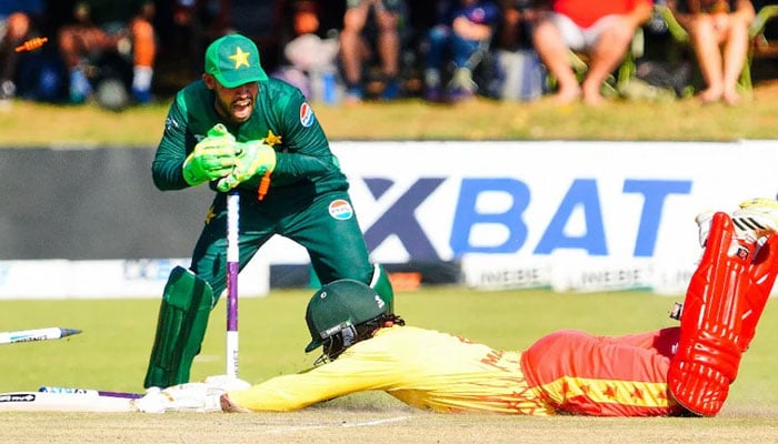 Pakistani wicket keeper Usman Khan (left) breaks the stumps as a Zimbabwean batter dives on December 1, 2024. — AFP