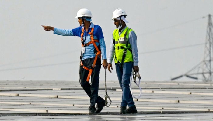 Solar technicians observing solar panels in India. — AFP/File