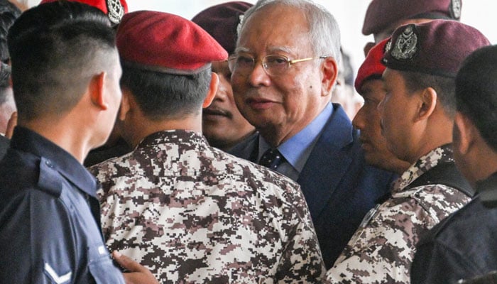 Former Malaysian prime minister Najib Razak (centre) can be seen crowded by police. — AFP/File