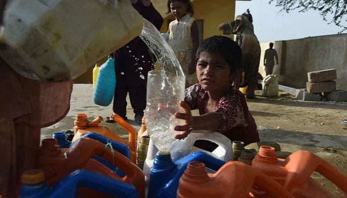 A girl fills her bottle from a water distribution point in Karachi.  — AFP/File