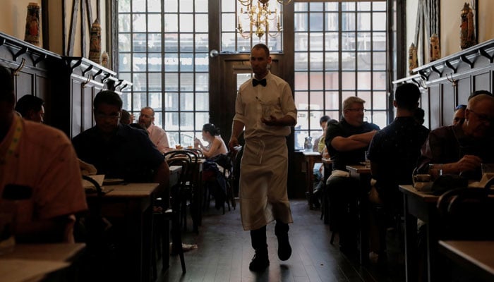 A waiter walks among diners at Peter Luger Steak House in Brooklyn, New York City, US, August 12, 2021. — Reuters