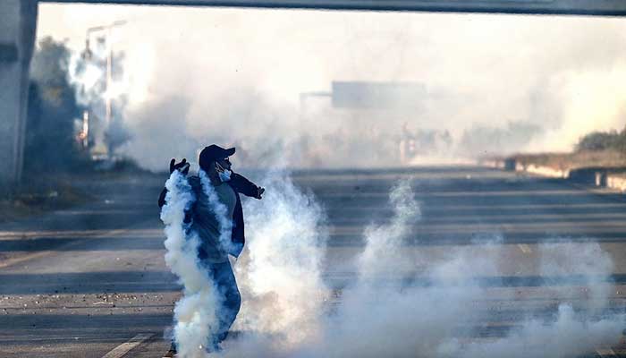 A PTI protester attempts to throw back teargas shells fired by riot policemen as they protest during a march to Islamabad in Hasan Abdal in Punjab province on November 25, 2024. — AFP