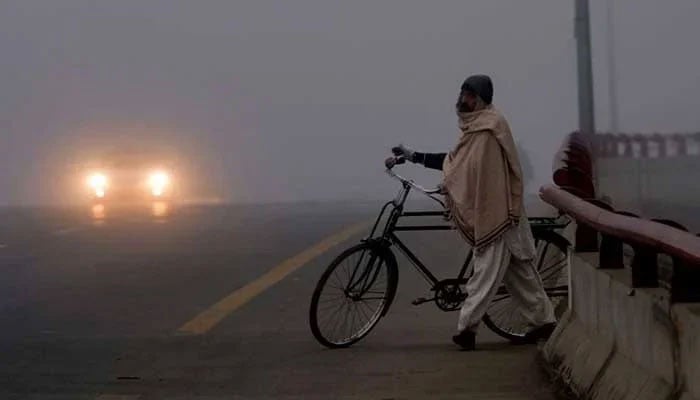 A man draped in a shawl makes his way across a bridge. — AFP/File