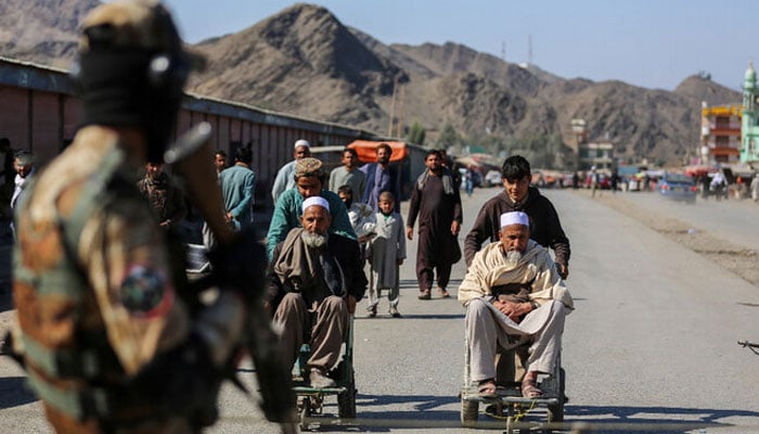 An Afghan soldier seen with a gun with wheelchair ridden elders in the background.— AFP/File