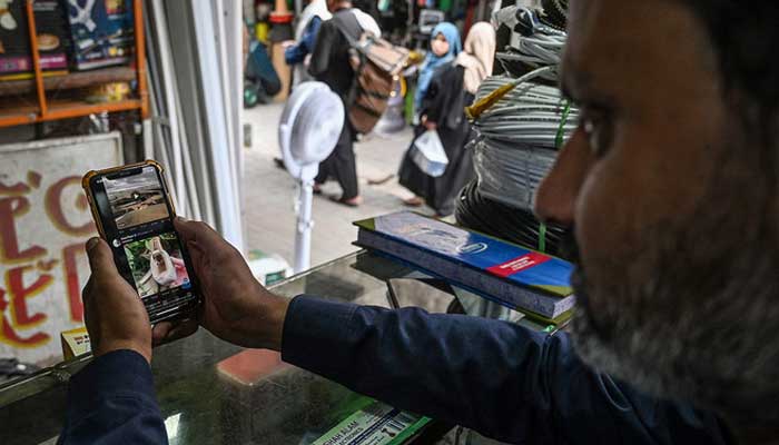 A man uses the social media platform X, formerly known as Twitter, on his phone at a market in Islamabad on April 17, 2024. — AFP