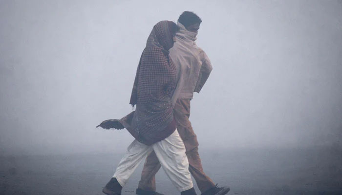 Two men wrapped in shawls to keep warm walk on a road on a cold winter morning. — Reuters/File