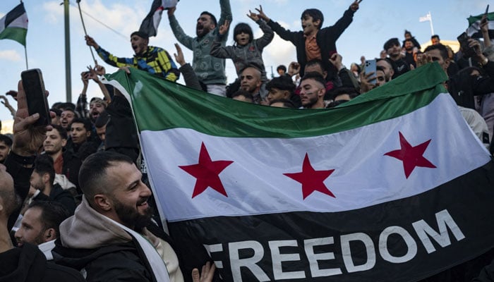 A demonstrator holds a Syrian opposition flag as members of the Syrian community chant slogans in Syntagma square in Athens to celebrate the end of the regime of Syrian dictator Bashar al-Assad after rebel fighters took control of the Syrian capital Damascus overnight, on December 8, 2024. — AFP