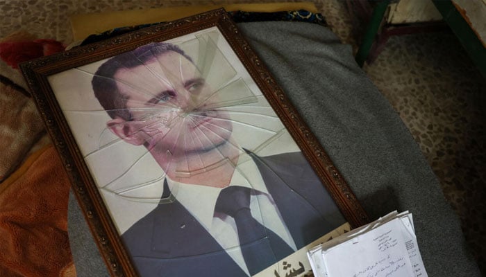 A portrait of Syrian President Bashar al-Assad is pictured with its frame broken. —AFP/File