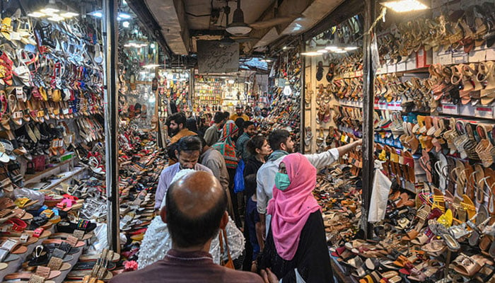 People shop at a market in Lahore on April 30, 2022. — AFP