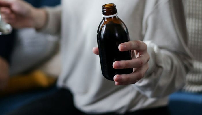 A representational image of a person holding a bottle of syrup. — Pexels/File