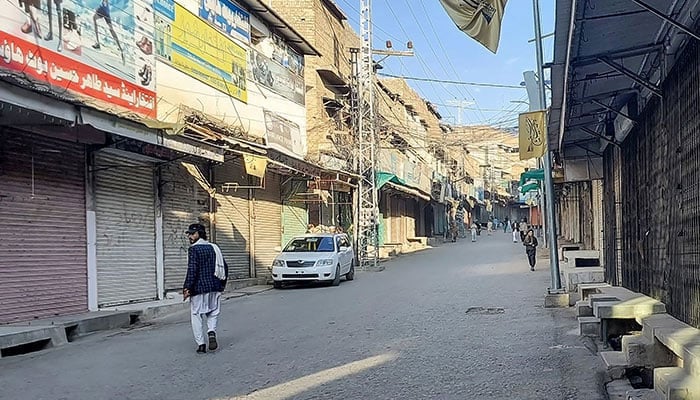 Men walk past a market closed by traders during a strike in Kurram district,  Parachinar, the mountainous Khyber Pakhtunkhwa province, on November 22, 2024. — AFP