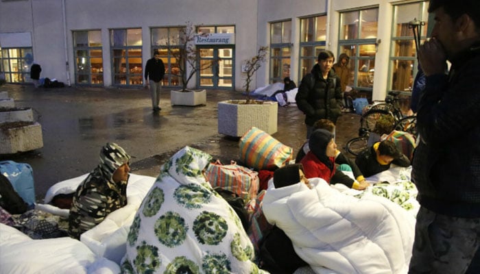 Refugees sleep outside the entrance of the Swedish Migration Agencys arrival center for asylum seekers at Jagersro in Malmö, Sweden, early November 20, 2015. — AFP