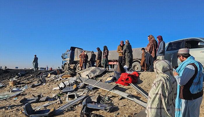 Afghan residents inspect the accident site as they stand near the remains of a bus following its collision with a coal truck on a highway between Kabul and southern Kandahar city, in the Andar district of Ghazni province, on December 19. — AFP