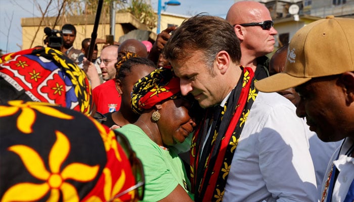 President Emmanuel Macron comforts a woman as he talks to residents in cyclone devastated Mamoudzou.— AFP/File