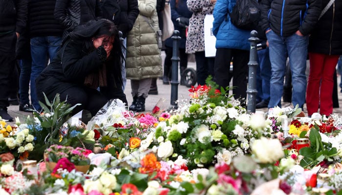 A woman reacts as people leave floral tributes to the victims near the site where a car drove into a crowd at a Magdeburg Christmas market in Magdeburg, Germany on December 21, 2024. — Reuters