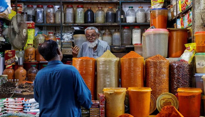 A shopkeeper speaks with a customer while selling spices at a market in Karachi on June 11, 2024. — Reuters