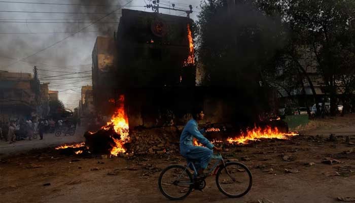 A boy rides past a paramilitary checkpost that was set afire by PTI supporters in Karachi on May 9, 2023. — Reuters