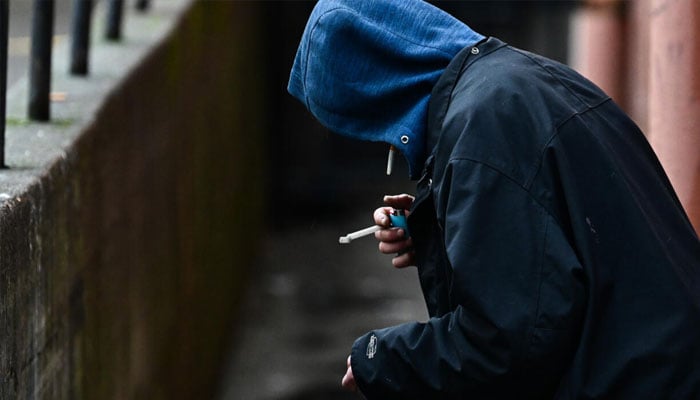 A person holds a lighter in an alleyway while smoking in the US state of Oregan in 2024. — AFP