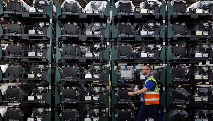 A worker walks past an assembly of the eDrives used in a variety of Ford electric vehicles, during a media tour of the Ford Halewood transmissions plant in Liverpool, Britain December 3, 2024. — Reuters