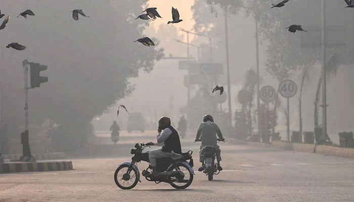 Commuters make their way amid smog in Lahore on November 2, 2024. — AFP