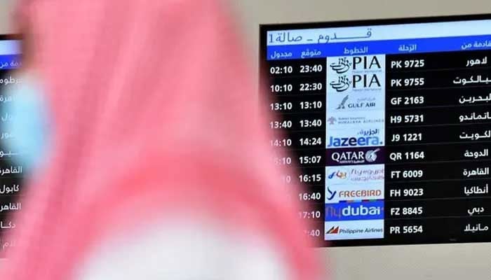 A representational image shows a passenger move past an electronic display of flight schedule at an airport. — AFP/File