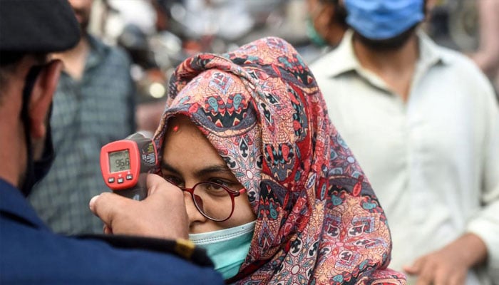 A security guard checking the temperature of a women. —AFP/File