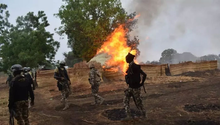 Nigerian military force soldiers standing near a burning house. —Nigeria Defence Headquarters/File