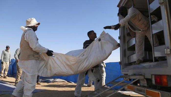 Forensic experts load human remains exhumed from a mass grave onto a truck in Tal Al-Shaikhia in the Muthanna province in southern Iraq on December 25, 2024. — AFP