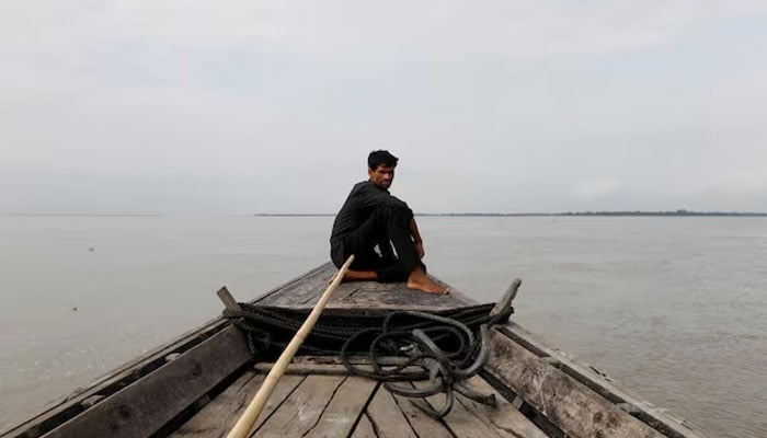 A man sits in a boat on the waters of the Brahmaputra river near the international border between India and Bangladesh in Dhubri district, in the northeastern state of Assam, India August 4, 2018.— Reuters