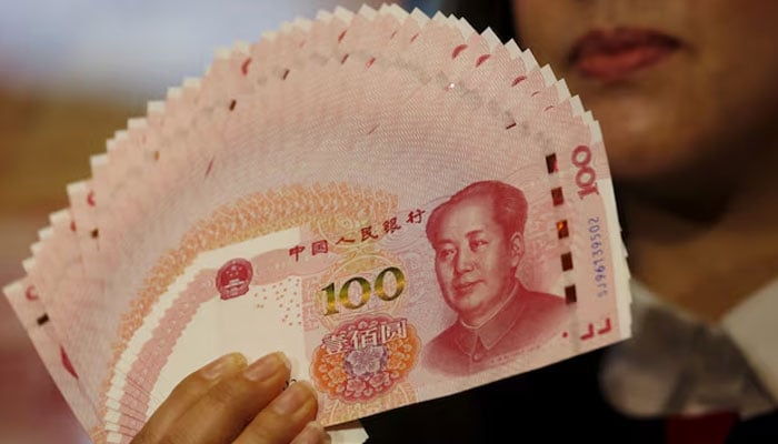 A staffer poses with 2015 edition of the 100 renminbi notes at the Bank of China Tower in Hong Kong, China November 12, 2015. — Reuters