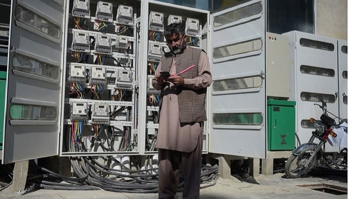 An employee of state-run Islamabad Electric Supply Company (IESCO), takes a meter reading with his smartphone at a commercial building in Islamabad. — AFP/File