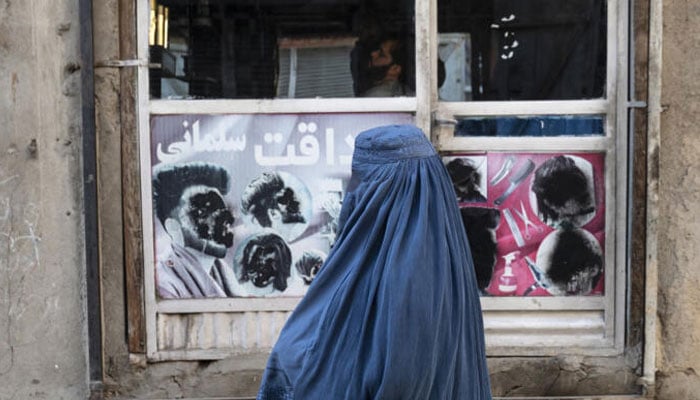 An Afghan woman stands by a window in Kabul on January 31, 2024.—AFP