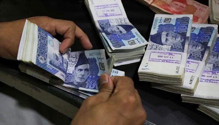 An employee counts Pakistani rupee notes at a bank in Peshawar on August 22, 2023. — Reuters